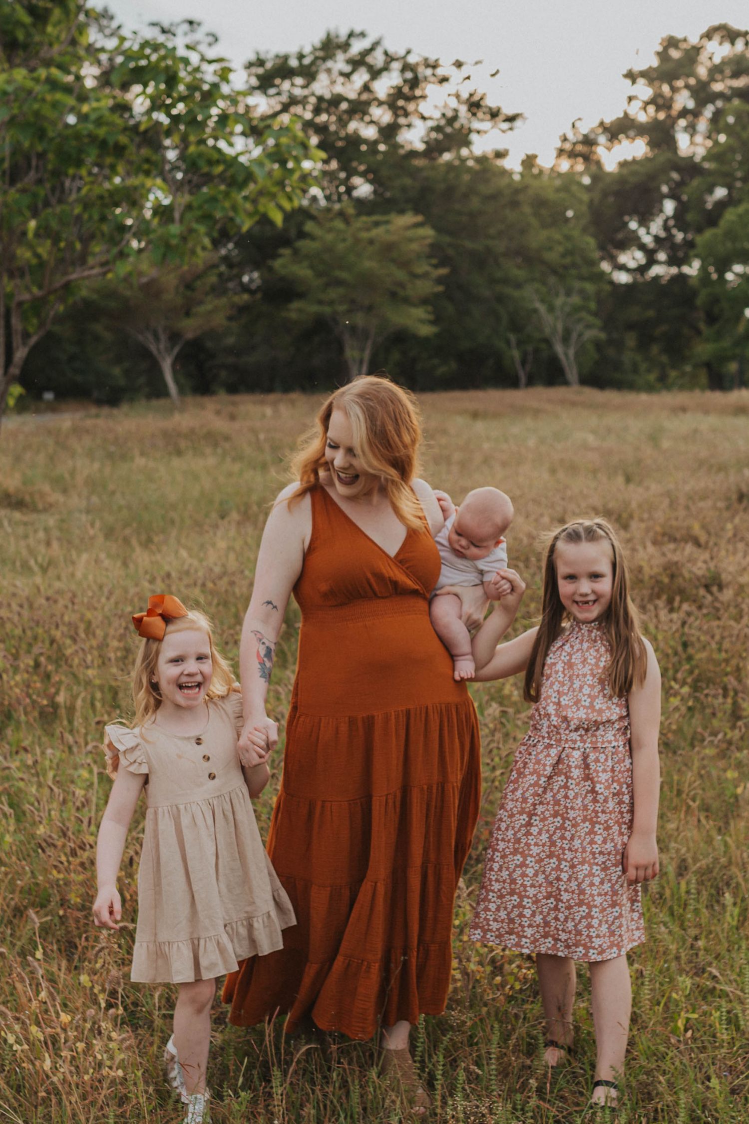 A family group wearing coordinated autumn-colored dresses standing in a field.