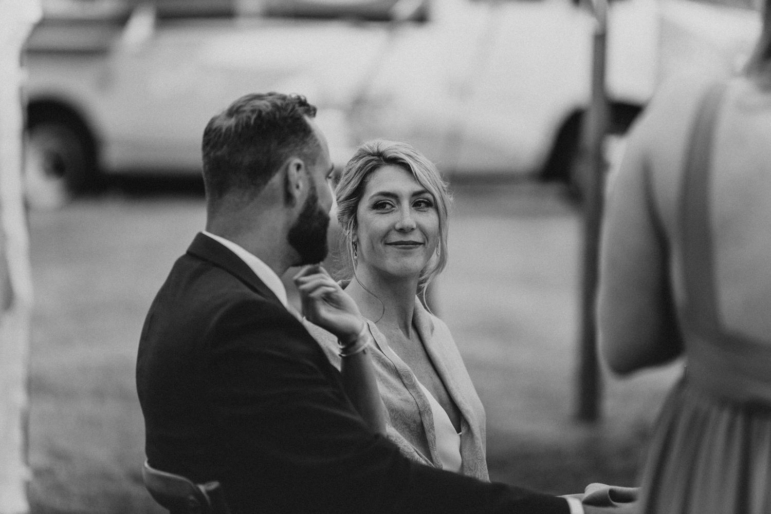 Black and white photo of wedding guests sharing joyful laughter during reception.