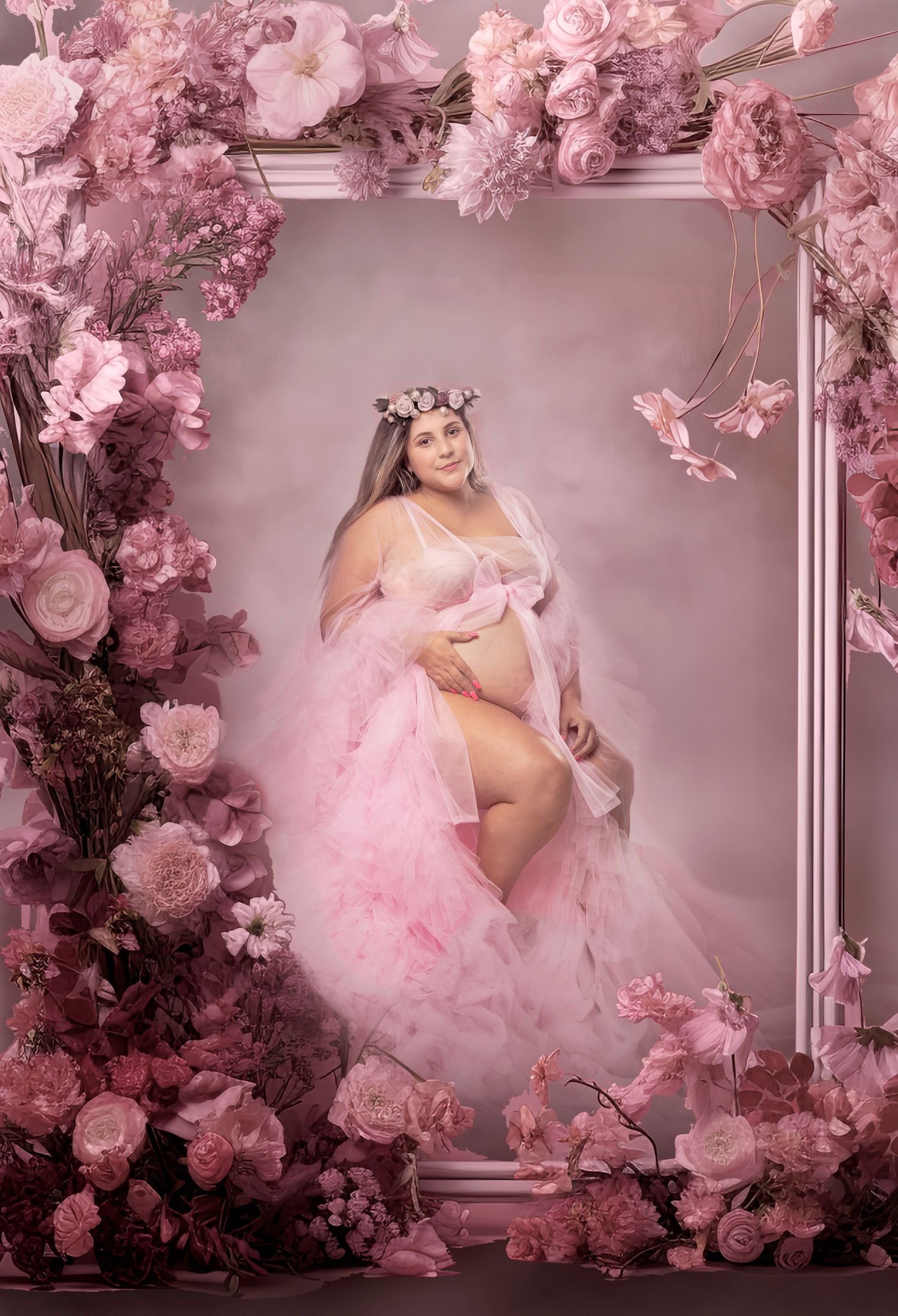 Dreamy maternity photoshoot with pink roses and tulle dress in soft lighting.