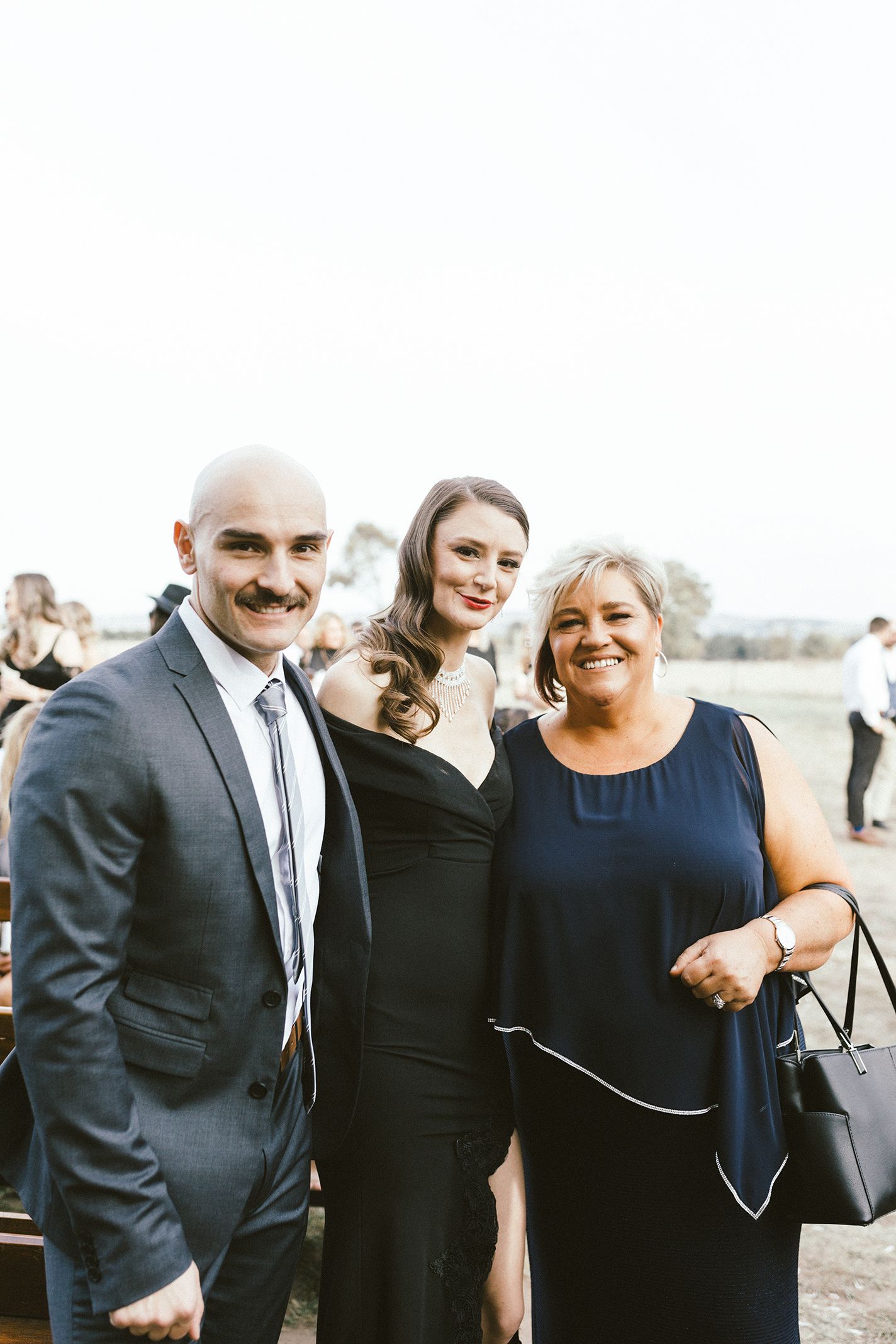 Formal event attendees in elegant attire posing together outdoors.