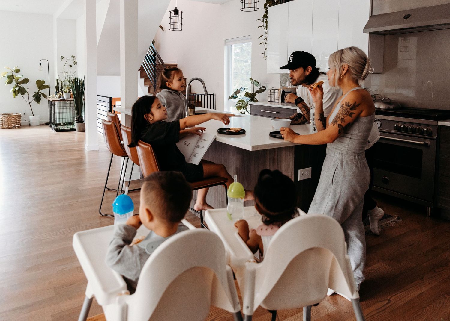 Gathering around a modern white dining table in a bright, airy kitchen.