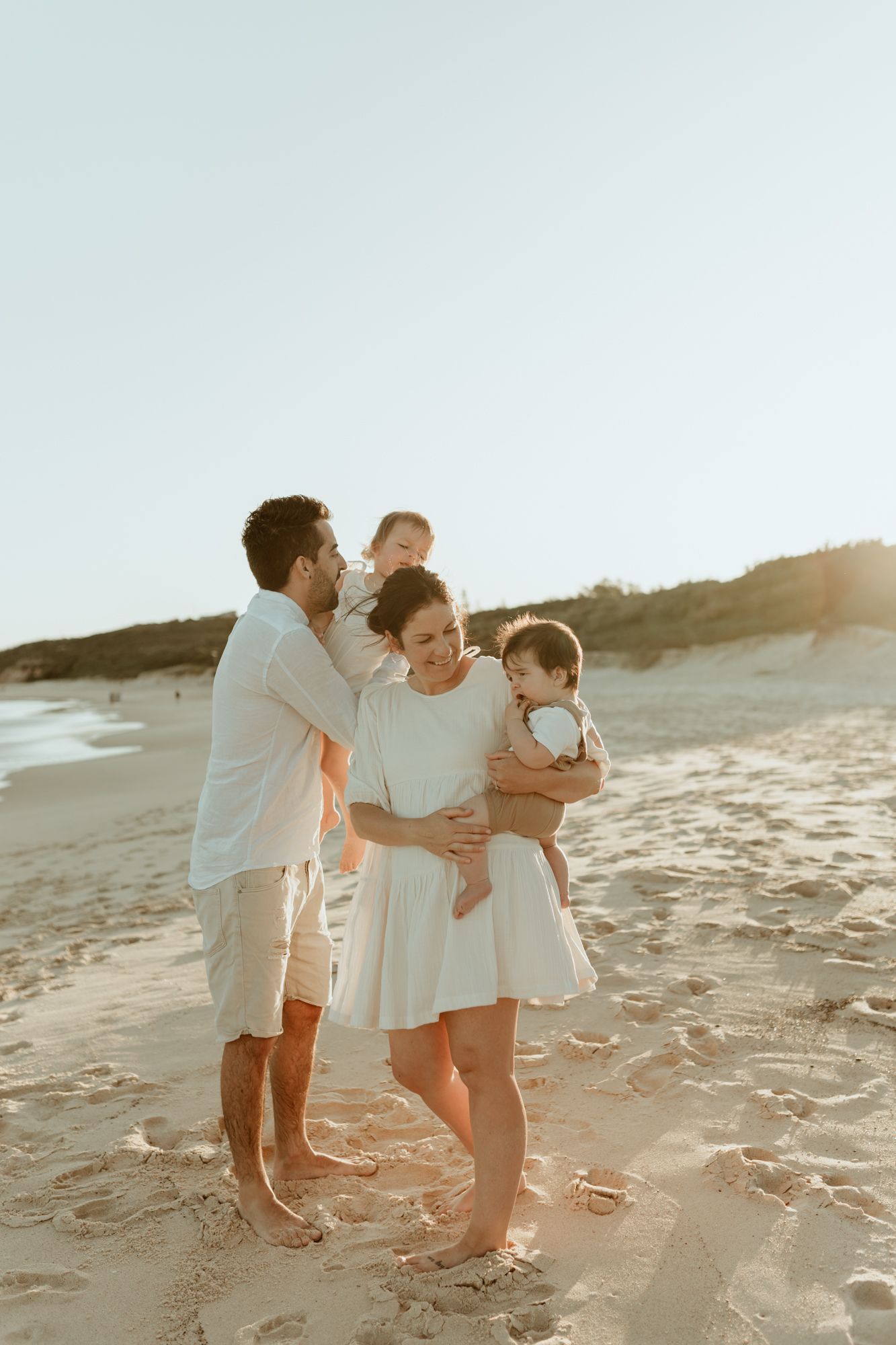 A family sharing a tender moment together on the beach during golden hour.