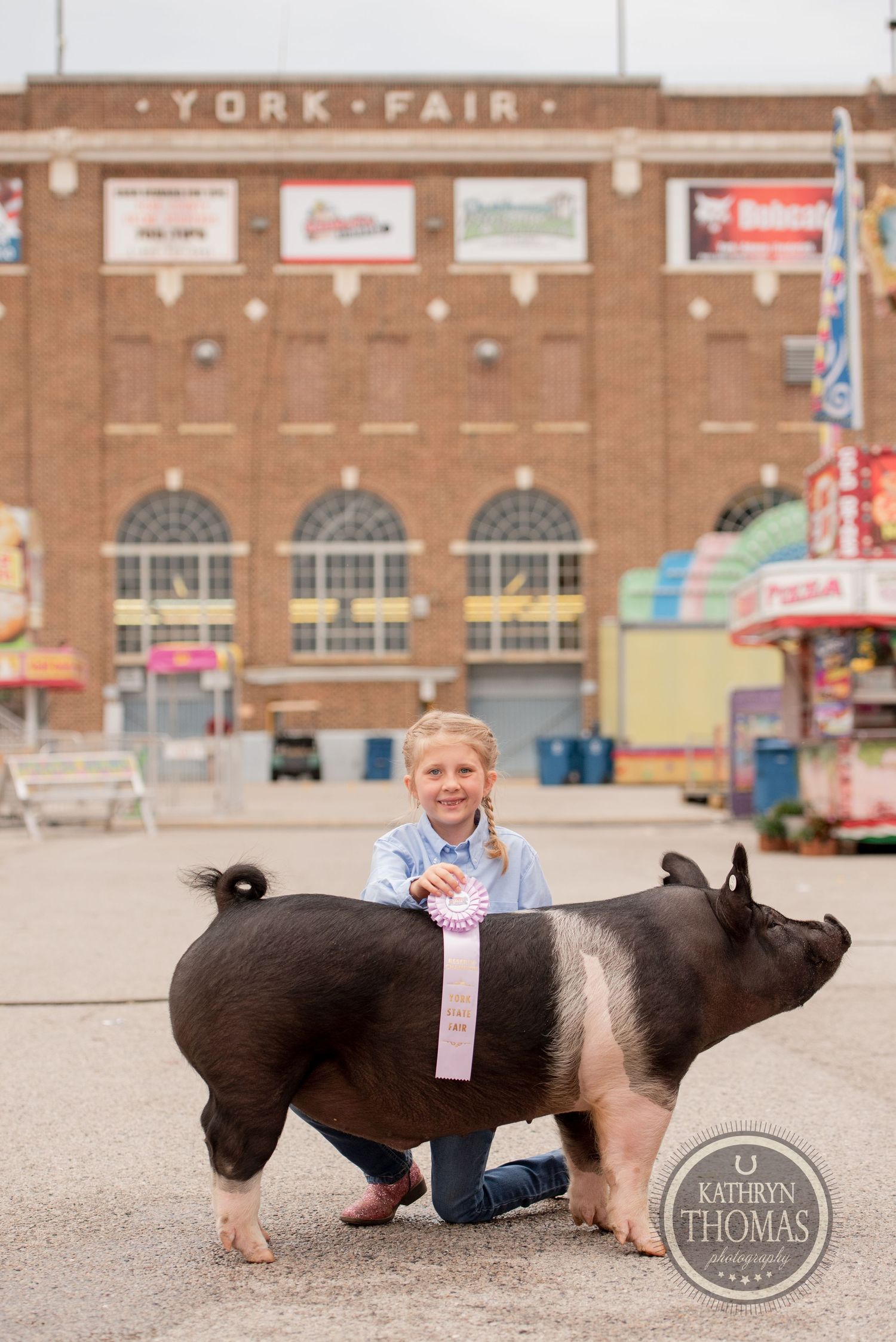A young exhibitor poses proudly with a prize-winning black and white pig at the York Fair.