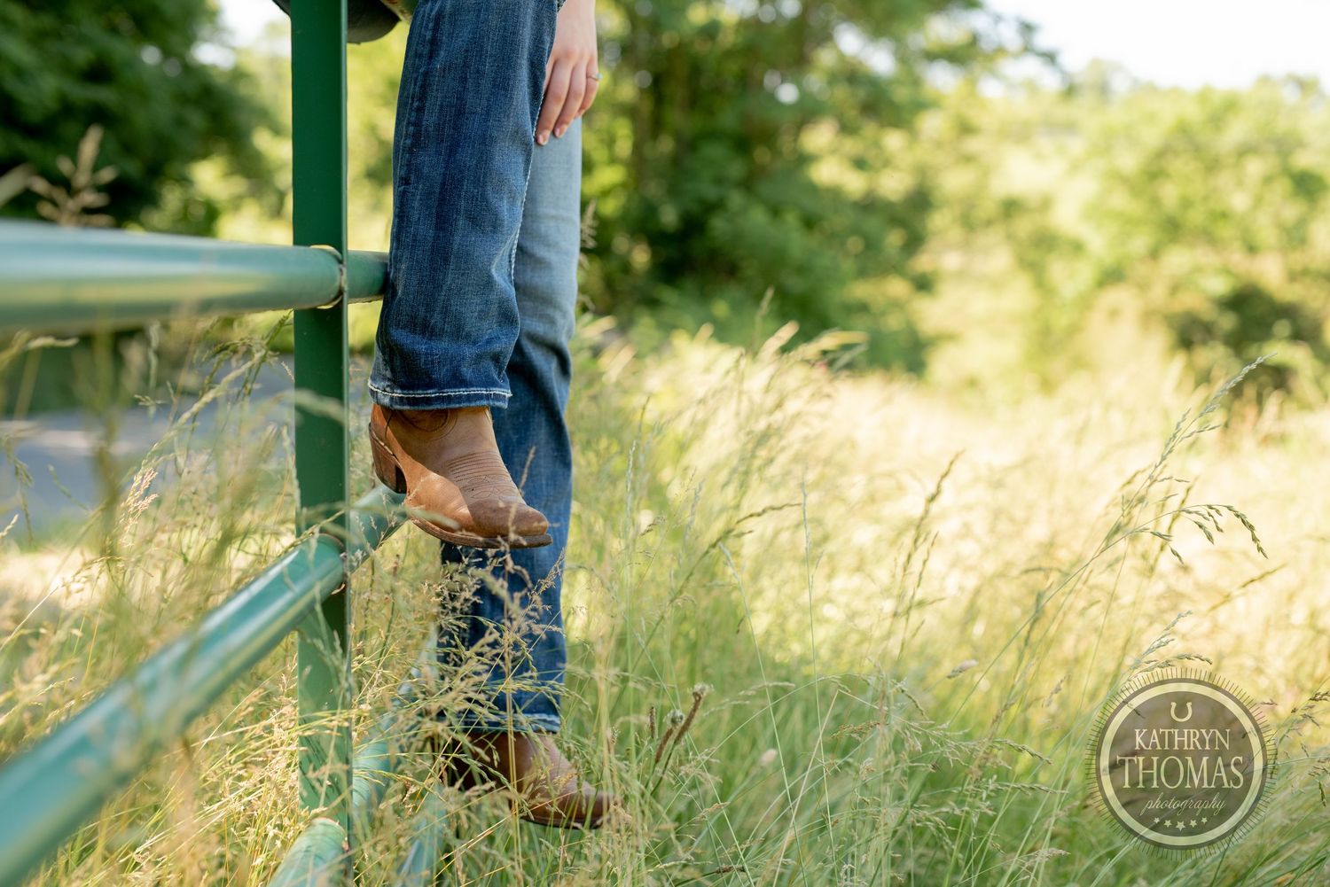 Detail shot of boots on a green metal railing with tall grass in the background.
