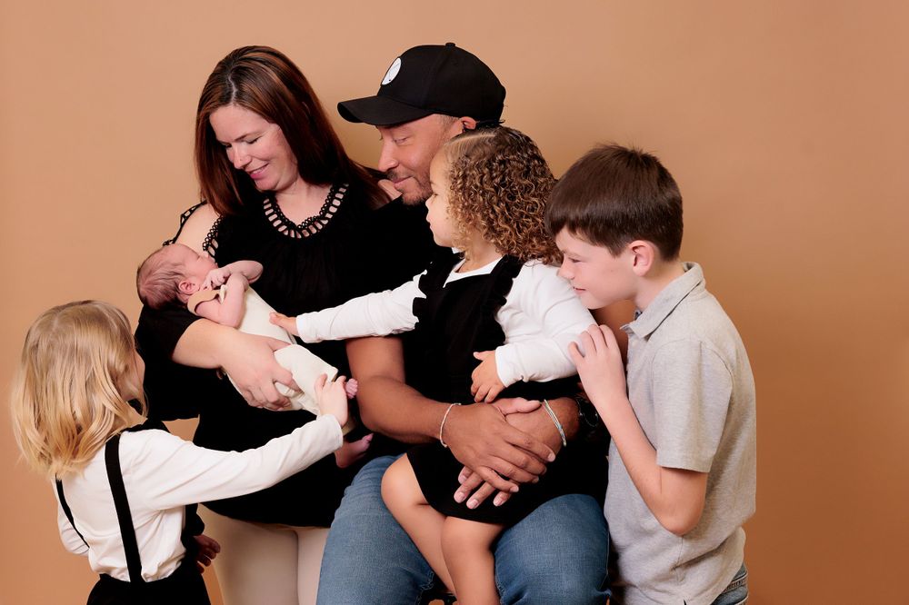 Family portrait with parents and children gathered together on brown background.