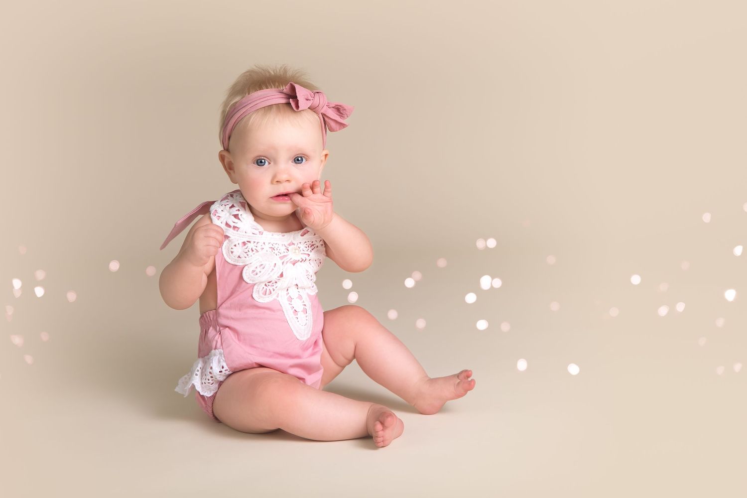 Baby milestone photo session with pink bow and sparkly background effects.