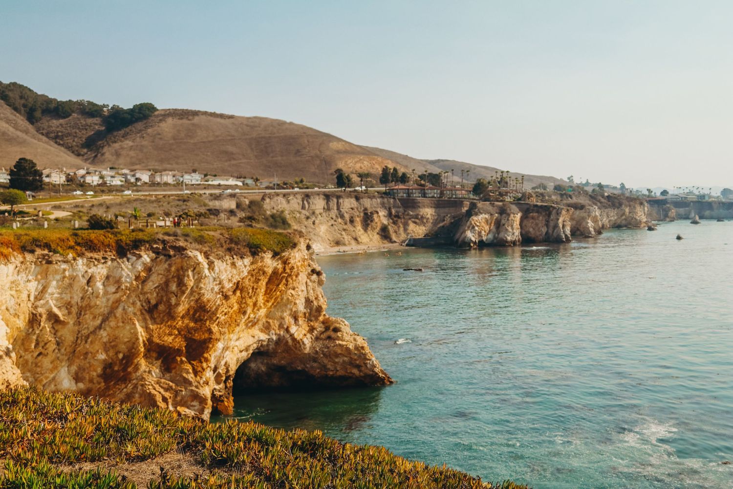 Coastal cliffs and rocky shoreline overlooking the blue ocean waters on a sunny day.