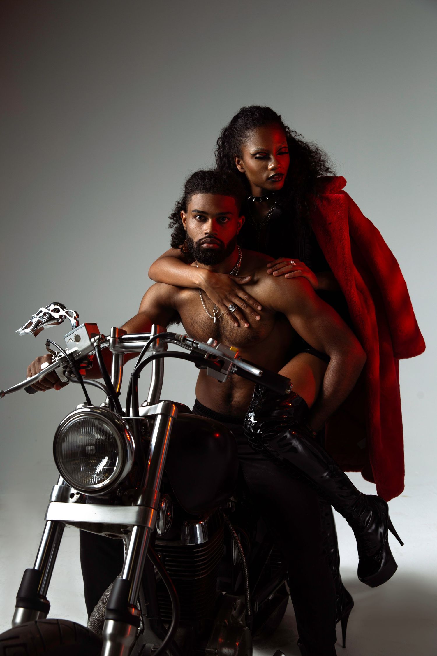 A man and woman posing on a motorcycle for a fashion editorial.