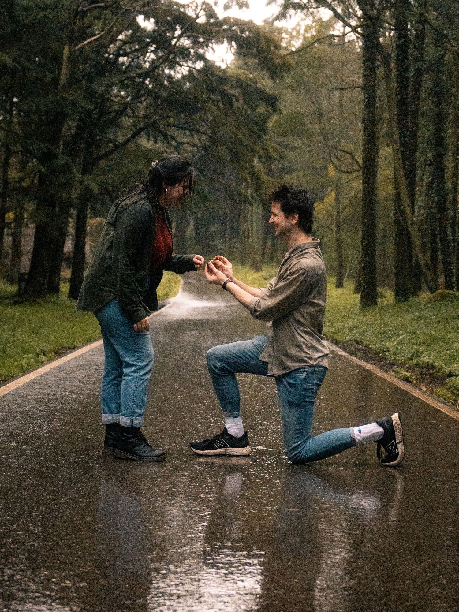 Marriage proposal sequence on a wet forest path with dramatic kneeling moment.