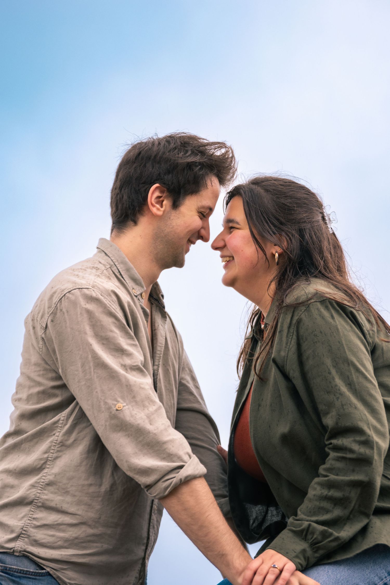 Two people sharing intimate moment against blue sky backdrop.