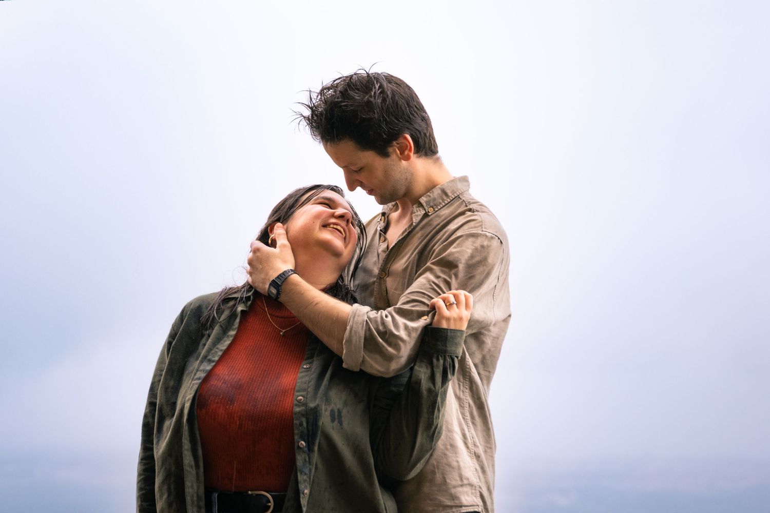Couple in casual attire sharing tender moment outdoors.