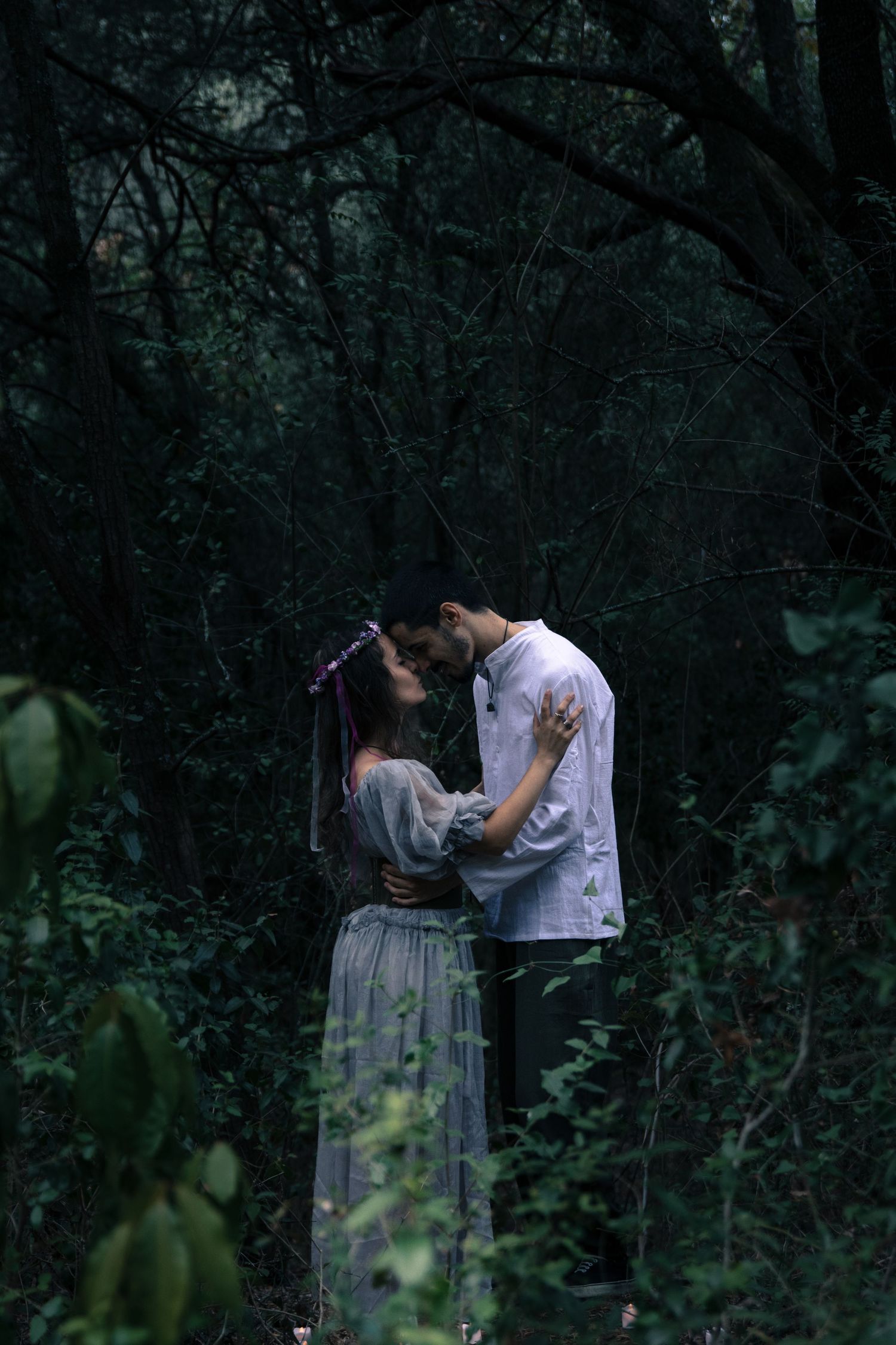 Intimate couple photos in a wooded setting with moody lighting and natural surroundings.