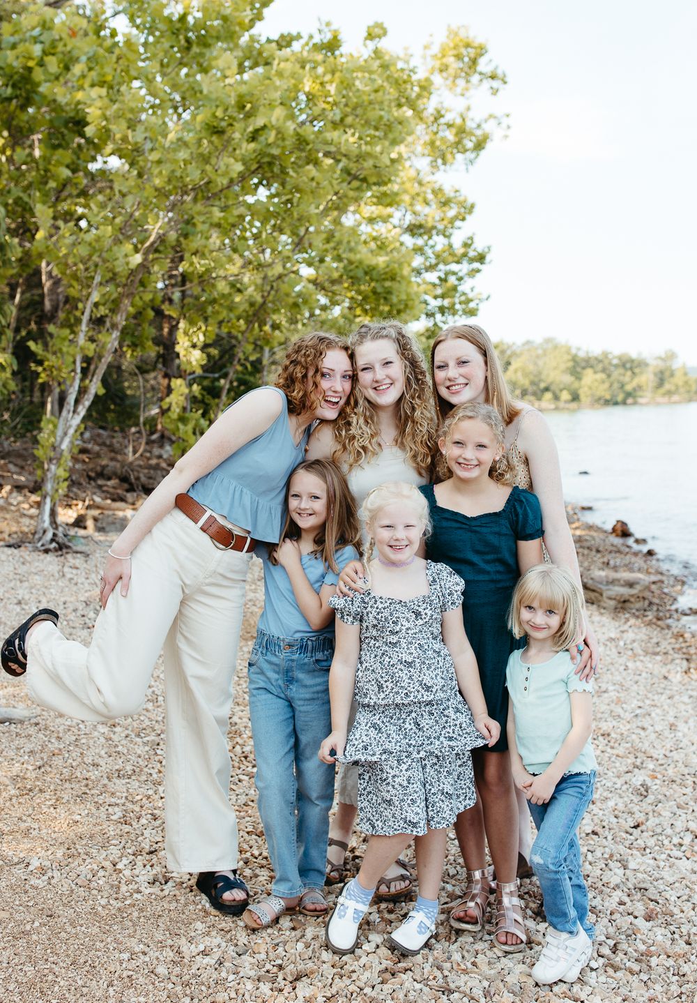 A cheerful group photo of women and children posing together by a lake.