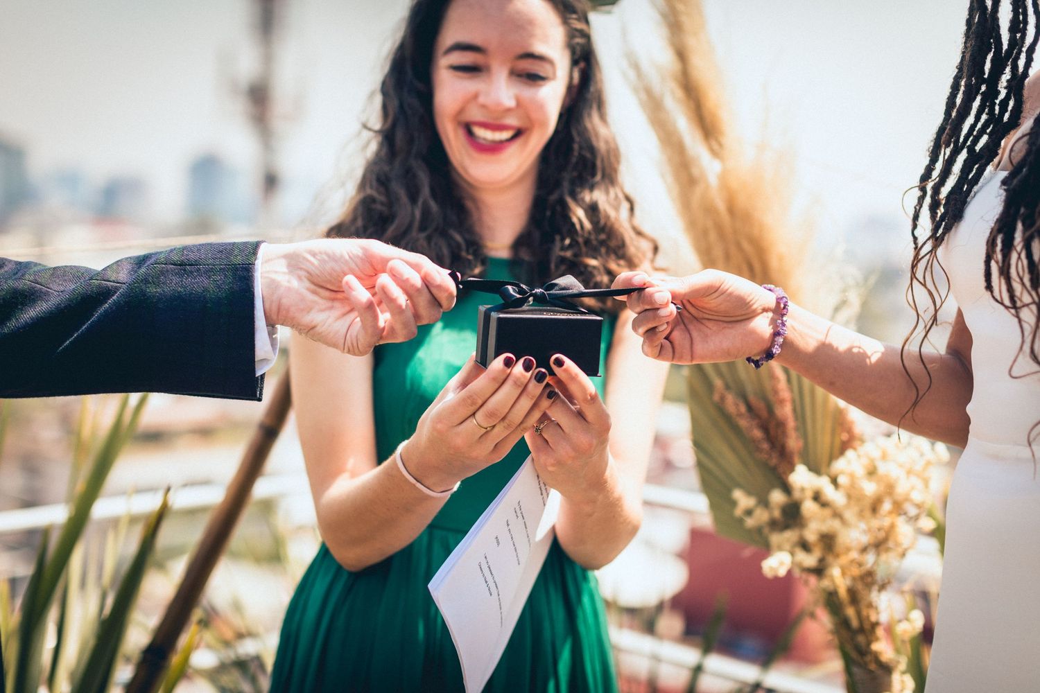 Friends in formal attire sharing joyful moments at an outdoor event.