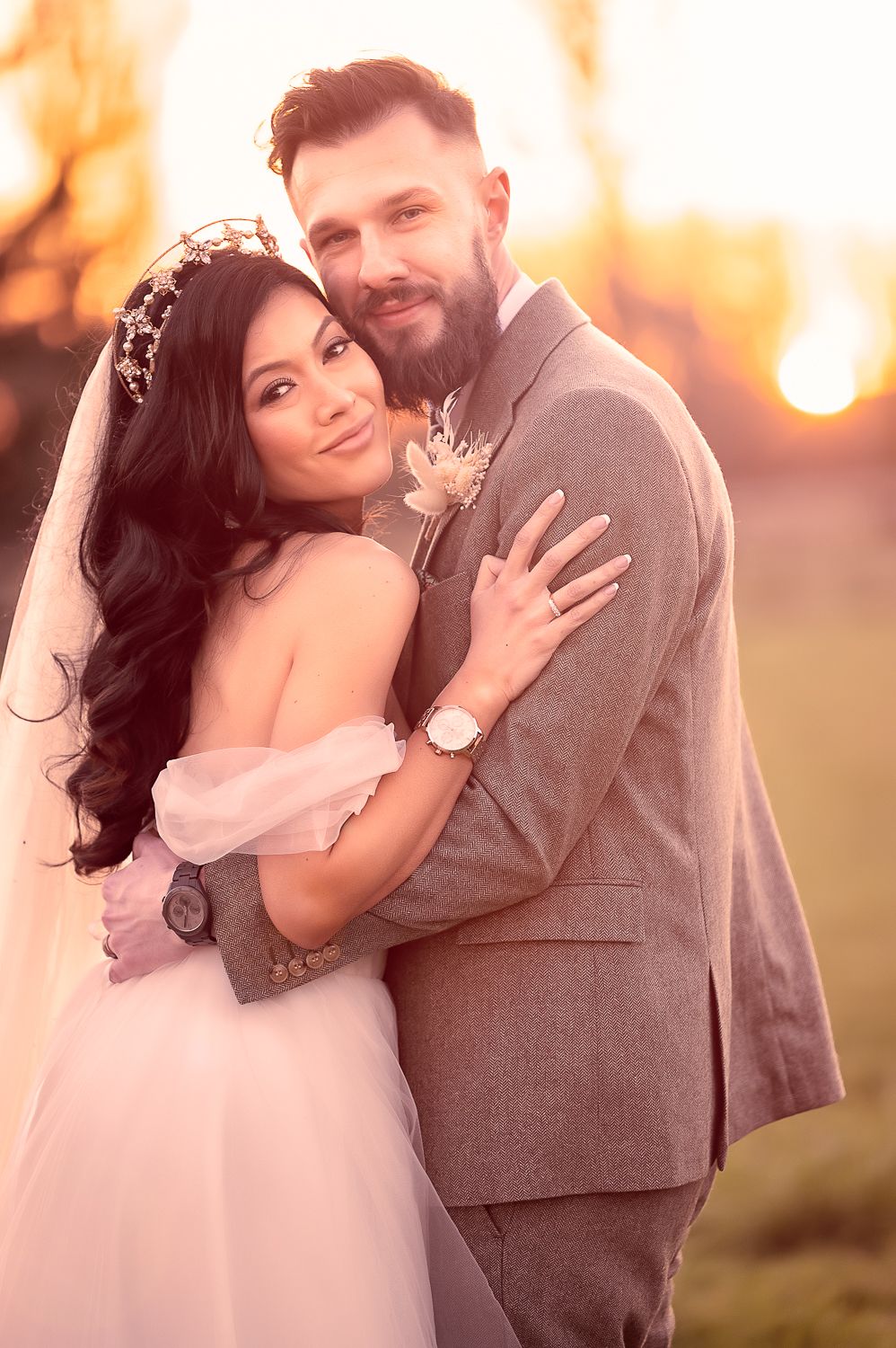 A romantic wedding portrait of a couple in formal attire during golden hour.