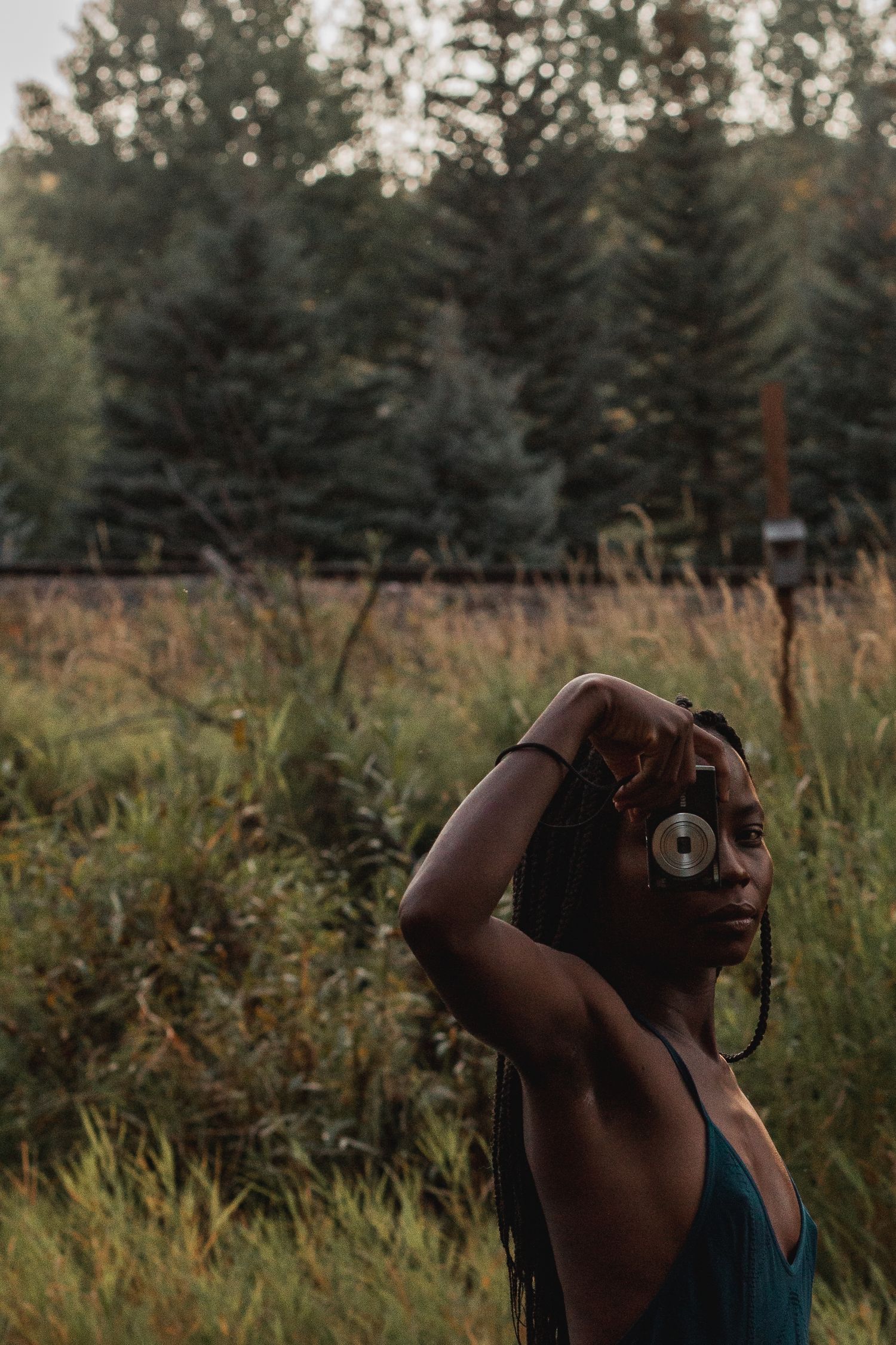 Artistic silhouette photo of someone taking pictures in a grassy field at golden hour.