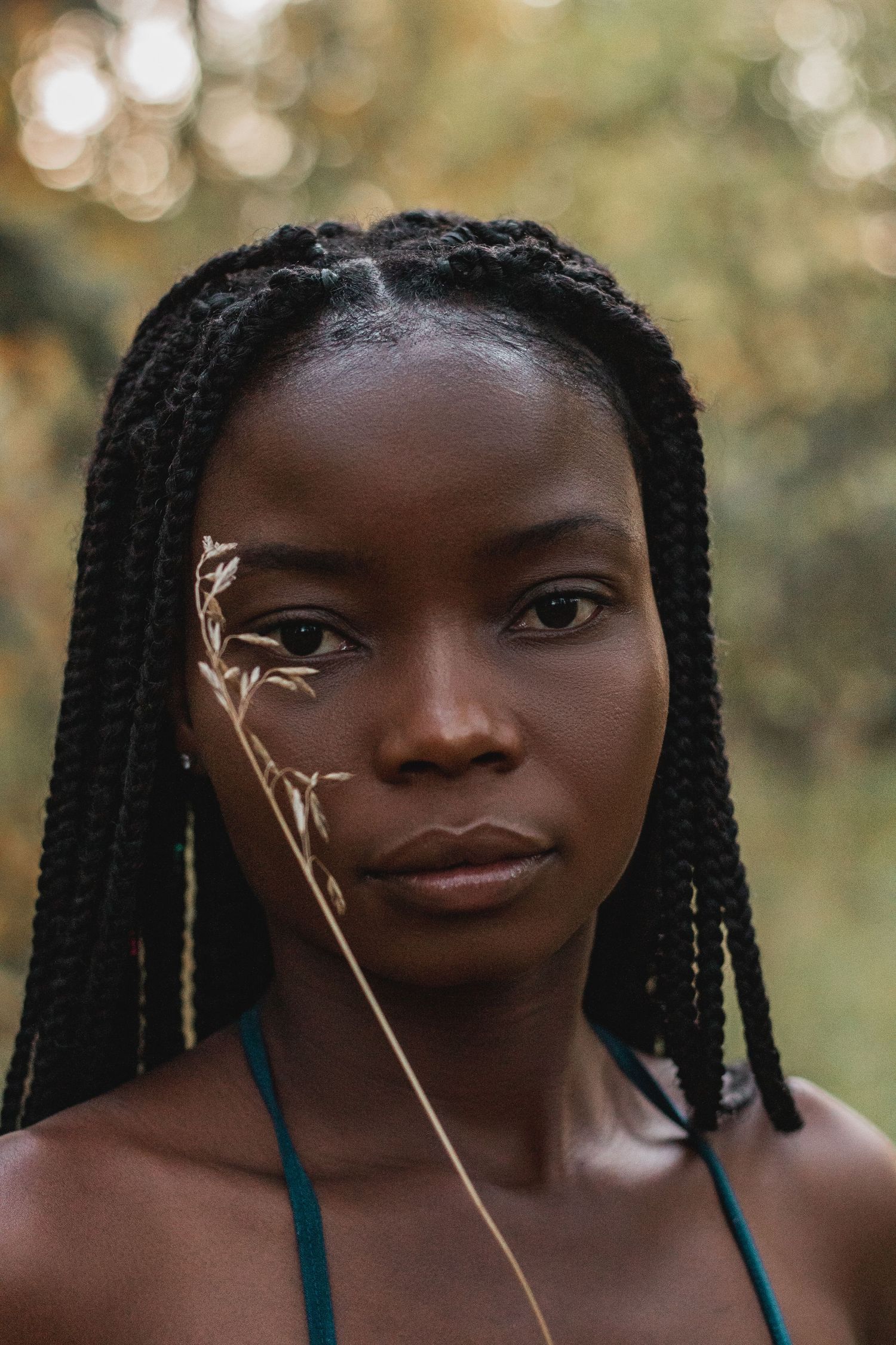 Portrait in nature showing decorative gold leaf accents against a soft bokeh background.