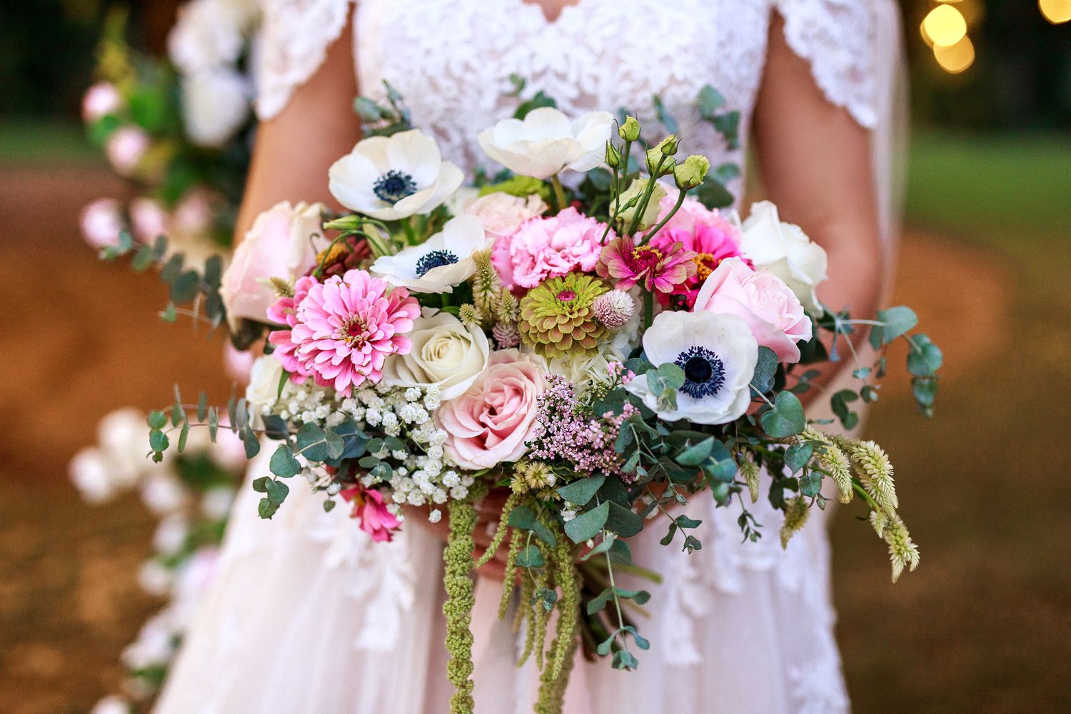 Pastel wedding bouquet with pink carnations, white anemones and mixed greenery.