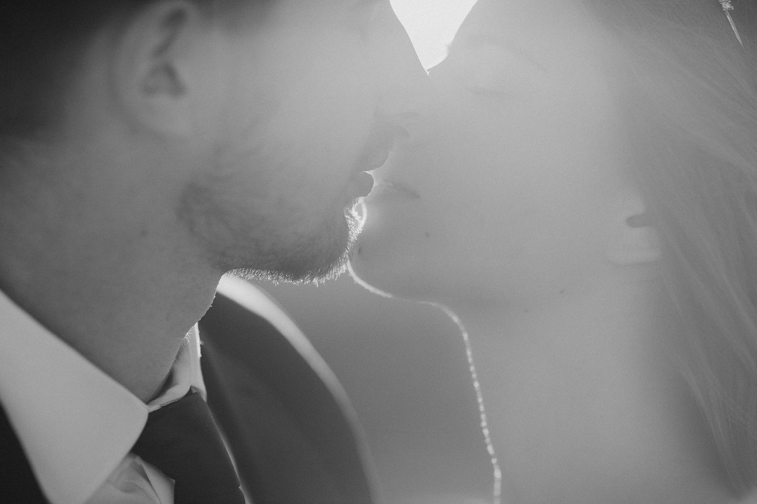 Close-up silhouette of a romantic couple sharing an intimate moment in soft lighting.