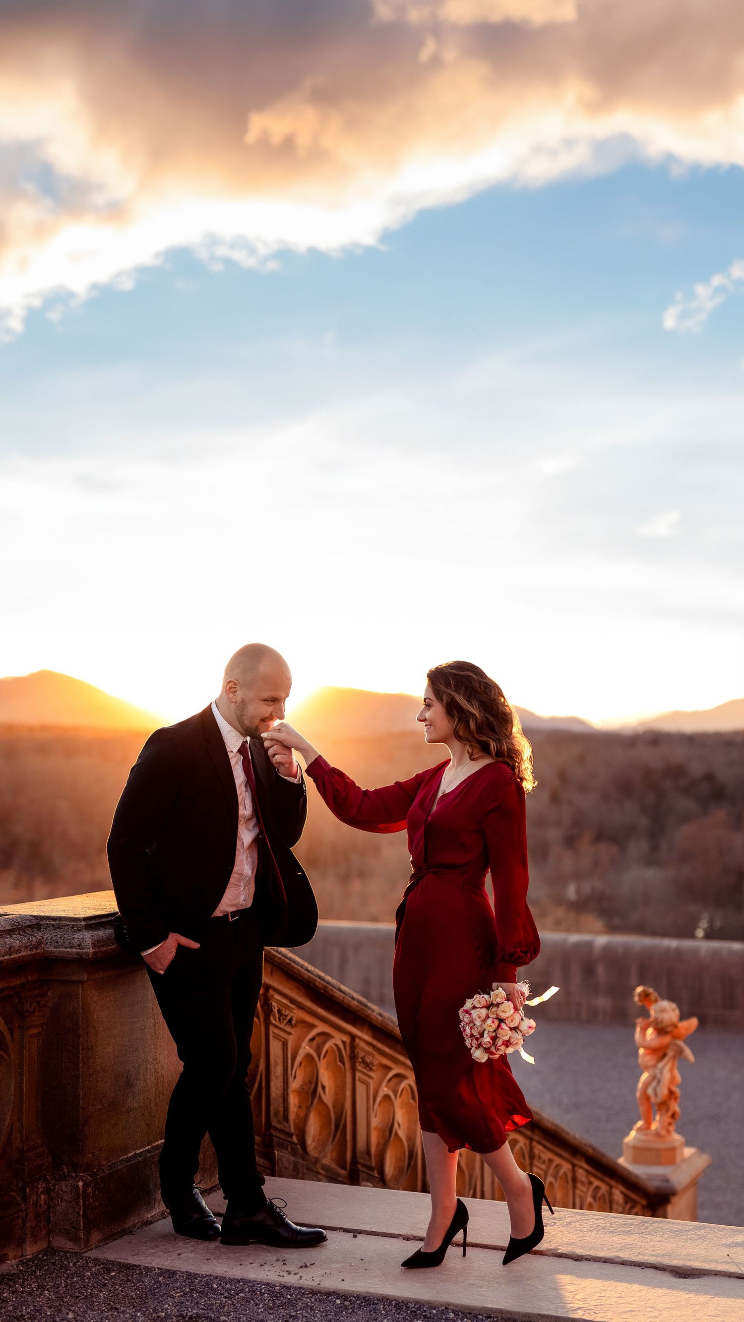 A romantic couple shares an intimate moment at sunset against a mountain backdrop.