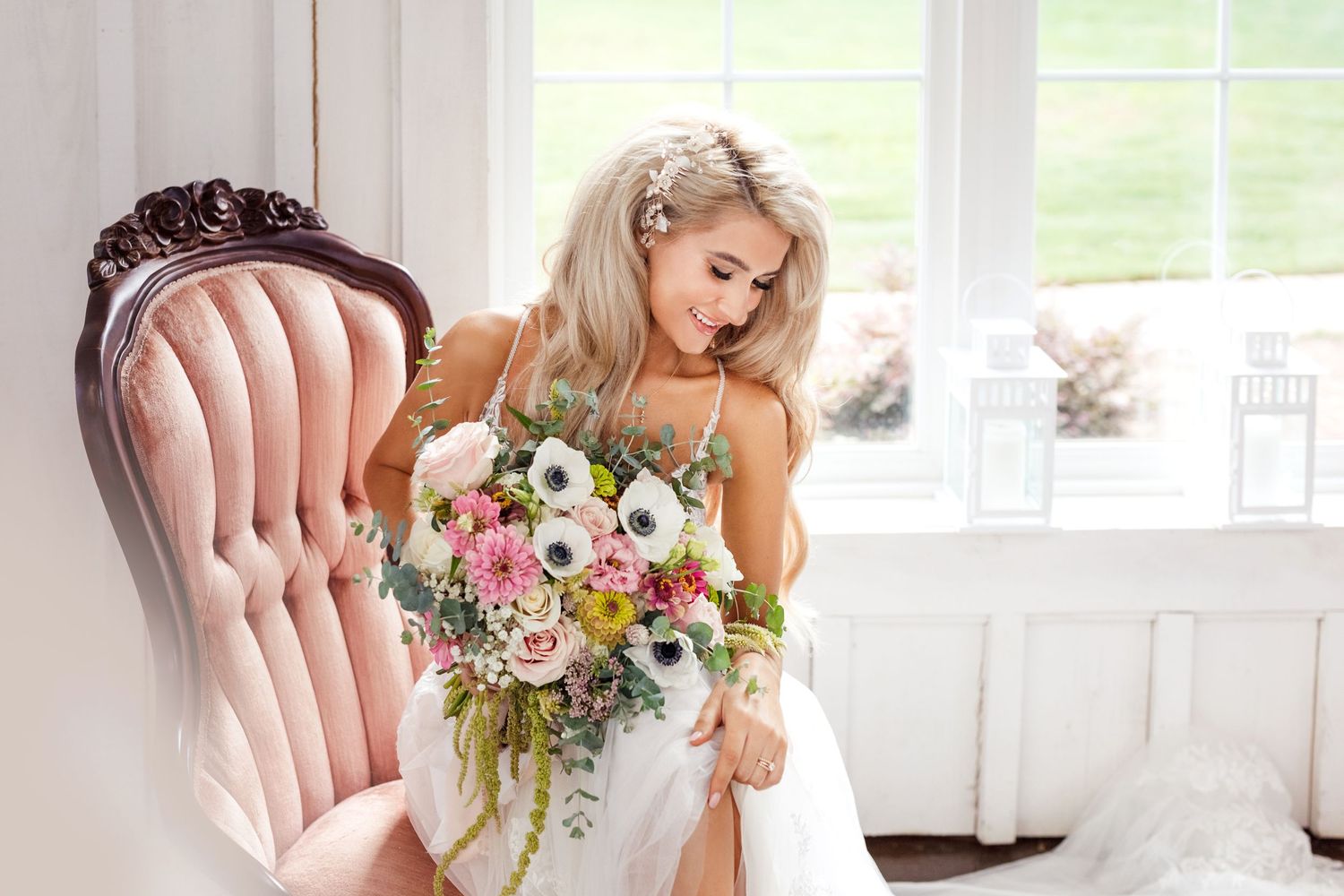 Elegant bride in vintage chair holds beautiful spring flower bouquet.