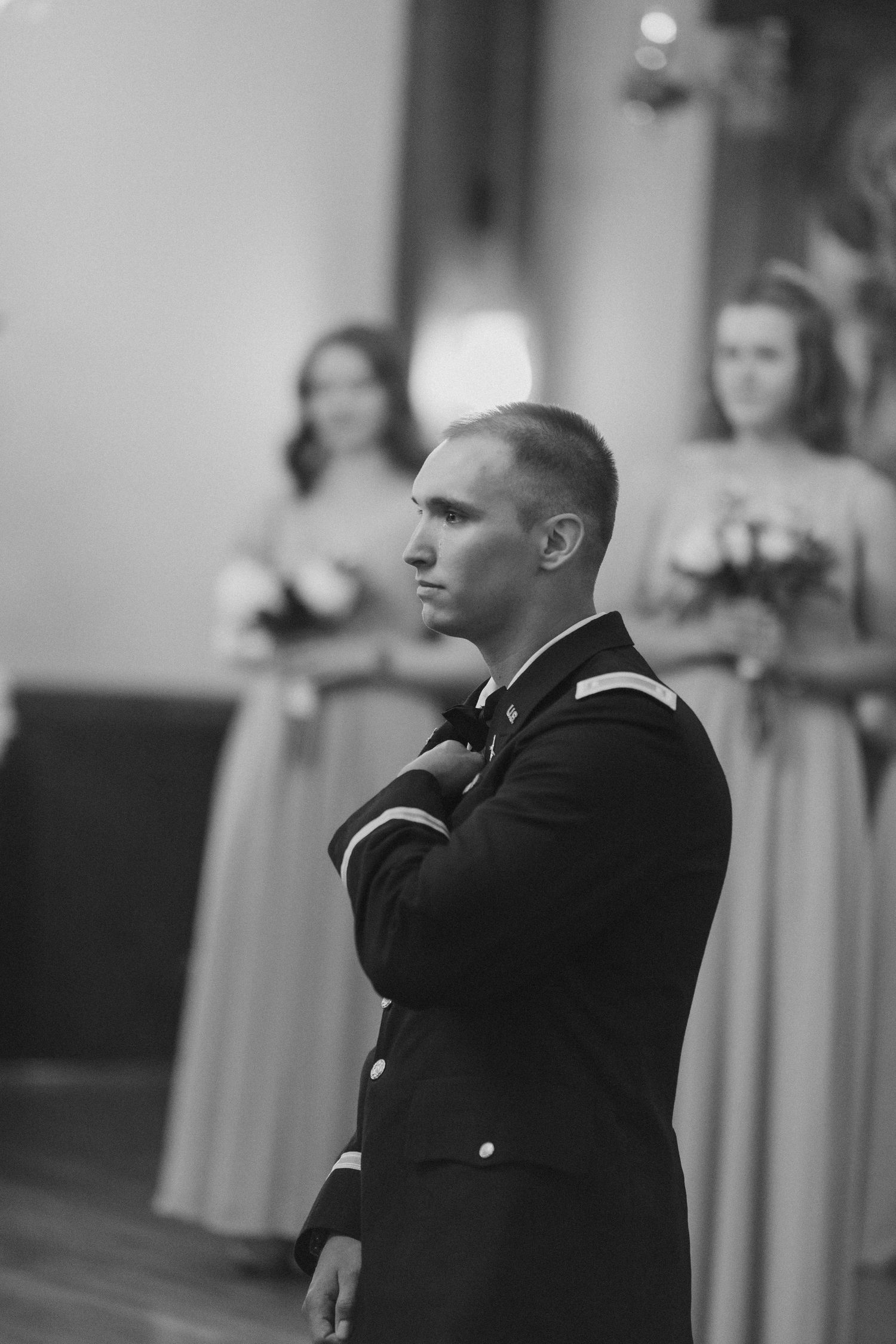 A serviceman in formal military dress uniform stands attentively during a wedding ceremony.