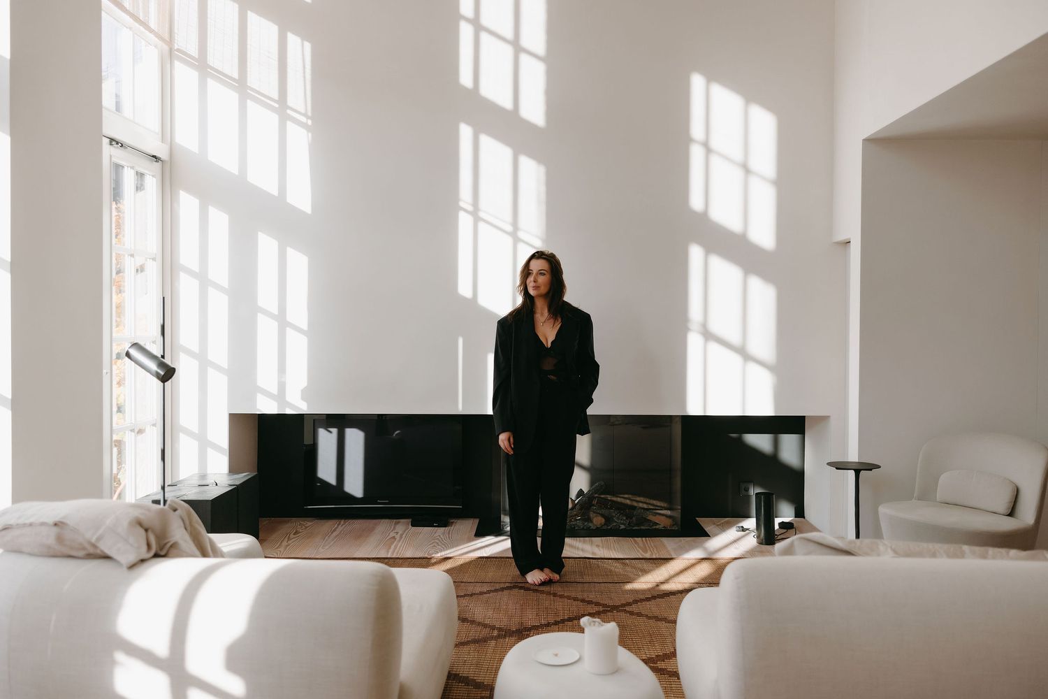 Modern minimalist room with large windows features elegant dark clothing display.