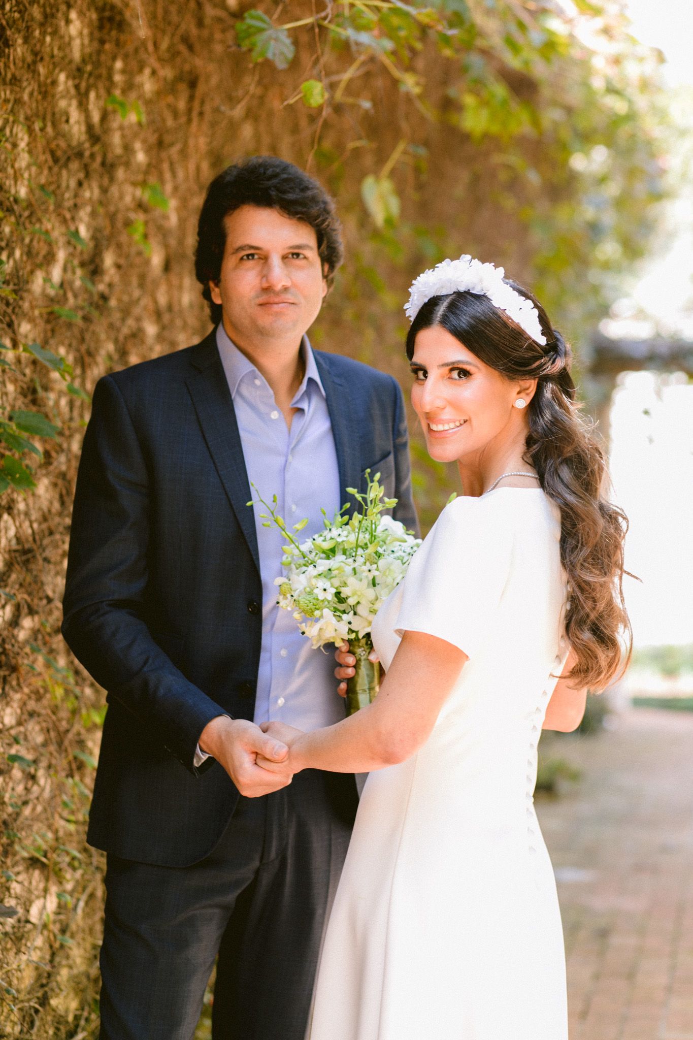 Romantic wedding portrait against vine-covered wall in natural light.
