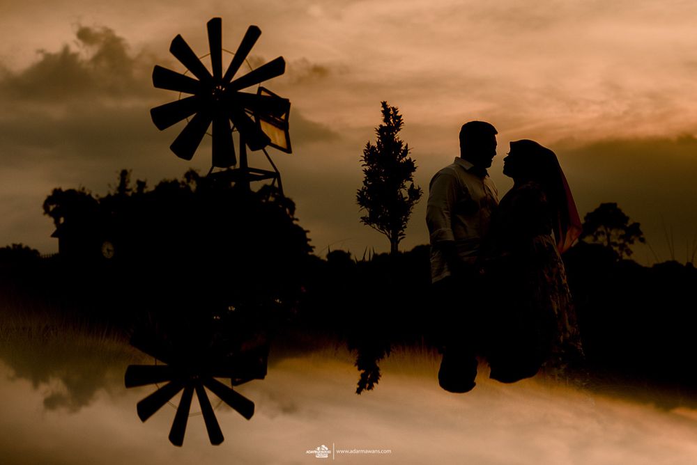 Silhouetted figures against a sunset sky with a windmill creating a romantic scene.