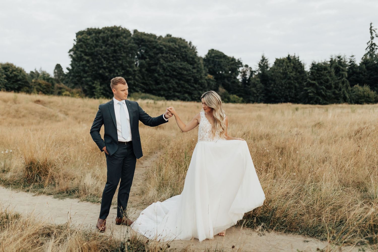 A couple poses playfully in a golden wheat field during their wedding photoshoot.
