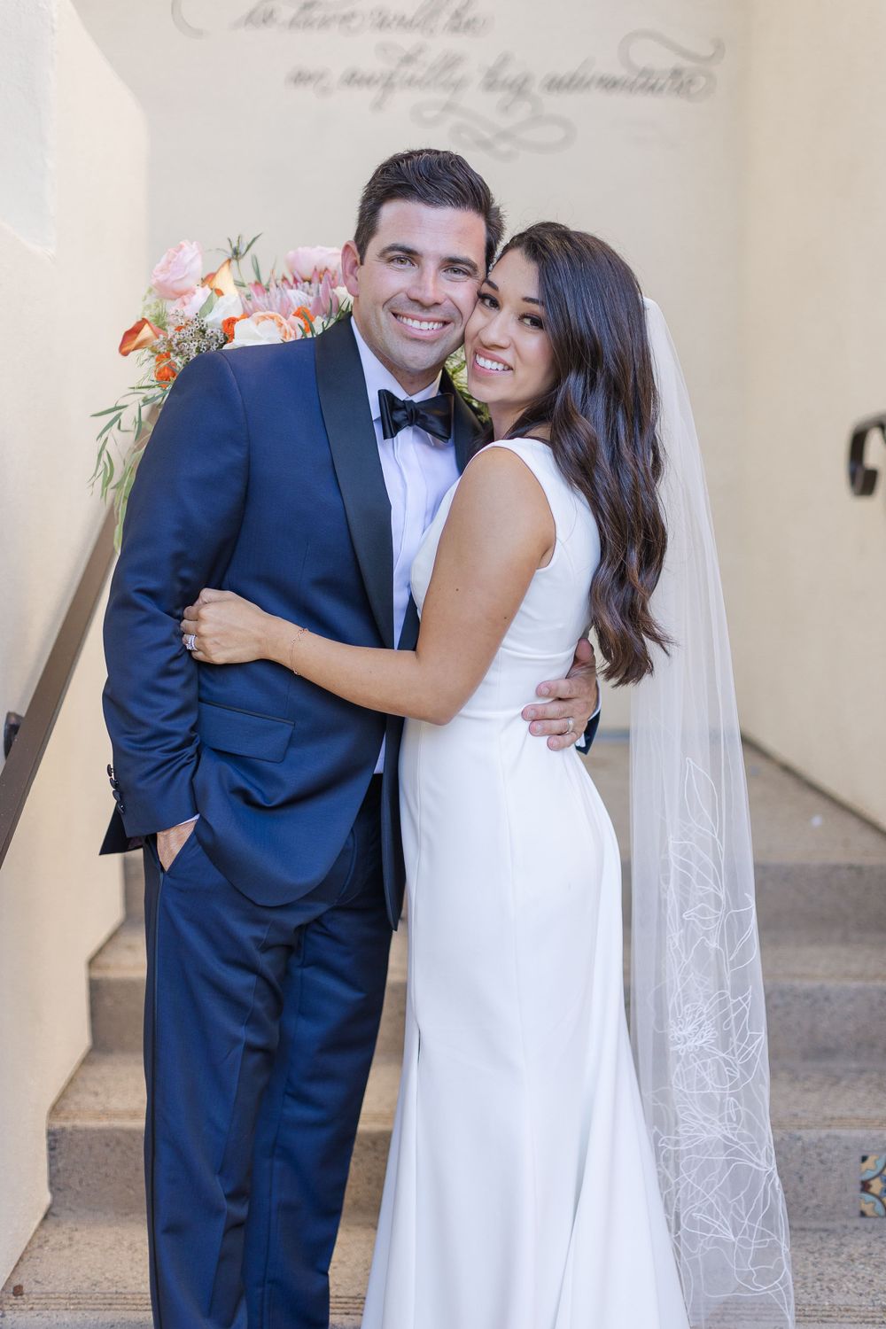 Husband and wife at Estancia La Jolla venue.  Groom is wearing a navy blue tuxedo.