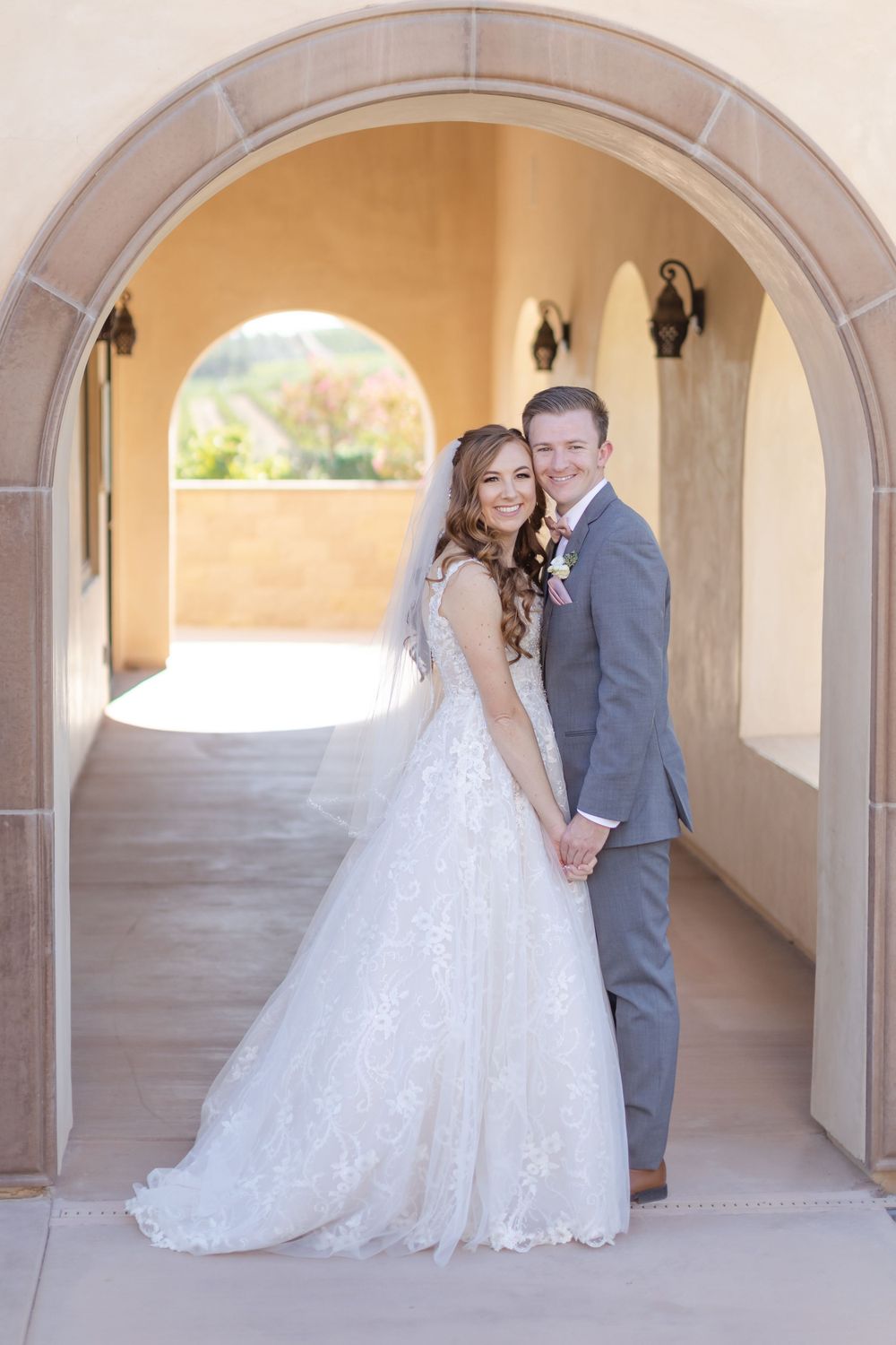 Gray Tuxedo Groom and red headed bride in an archway at a winery.