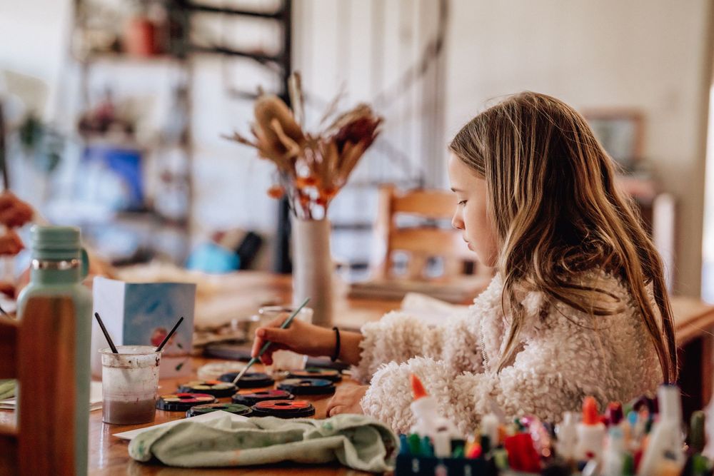 A young girl painting at the family dining table in Perth
