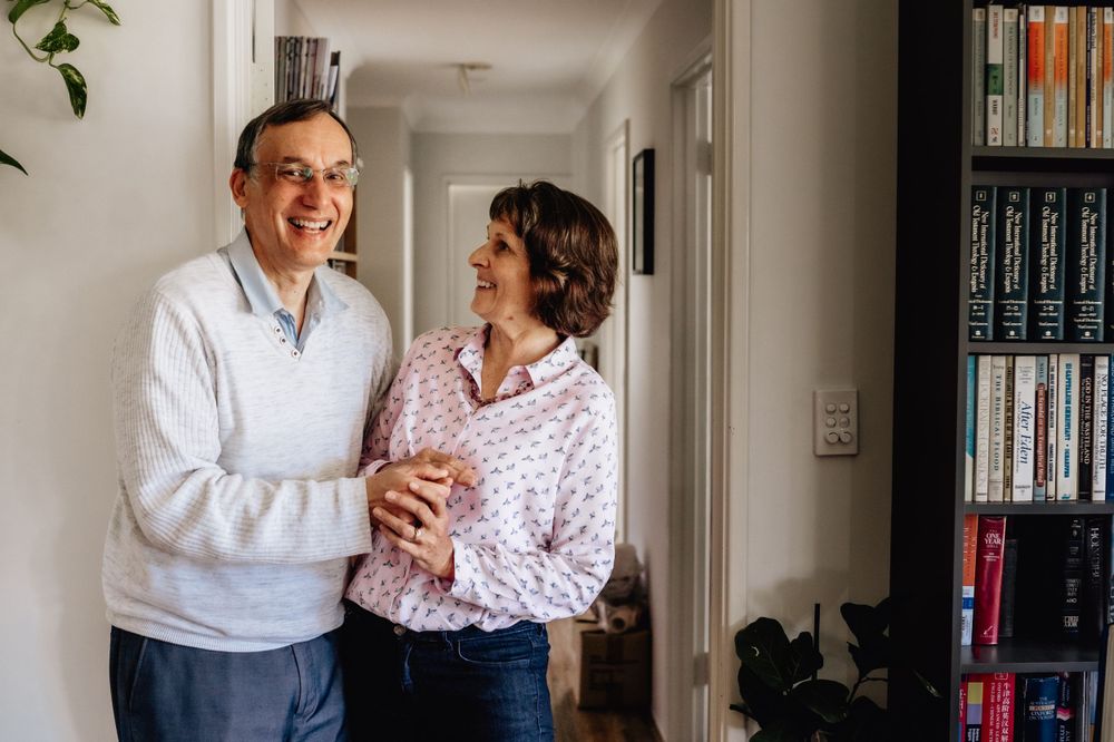 A grandmother and grandfather hugging and laughing in their home