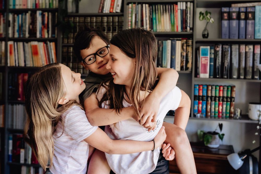 Three siblings laughing and looking at each other in their lounge room