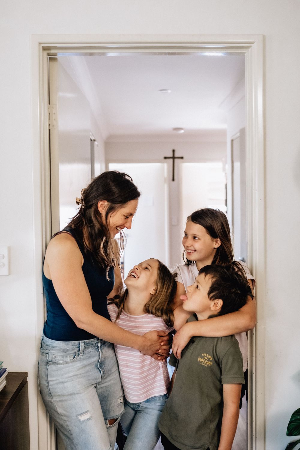 Motherhood- a mum standing with three children looking at her in their home