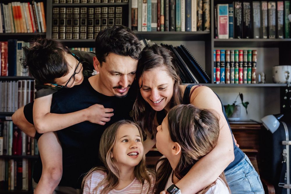 A family with three children cuddling and looking at each other during a family photo session