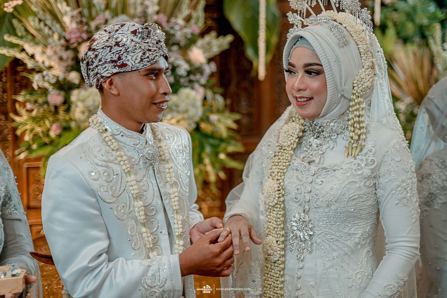 Couple in traditional white wedding attire sharing a happy moment.