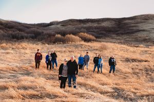 Large extended family group portrait taken on golden prairie grasslands under a wide open sky.