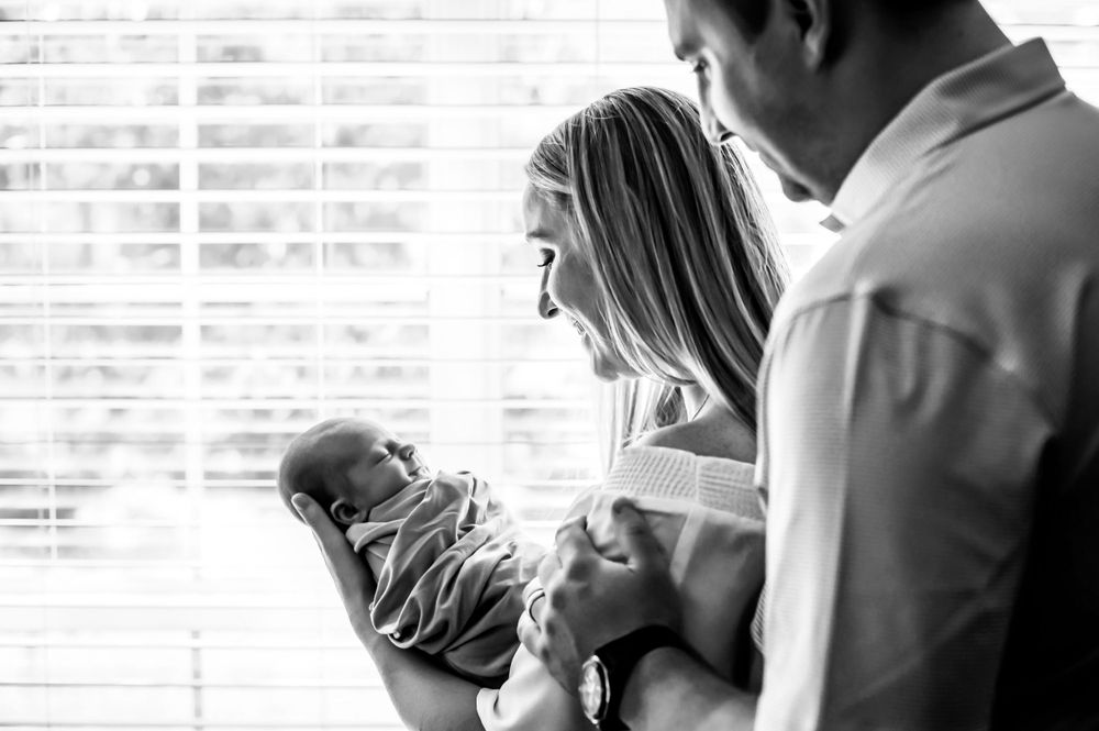Loving family moments captured in soft sunlit images with a newborn.