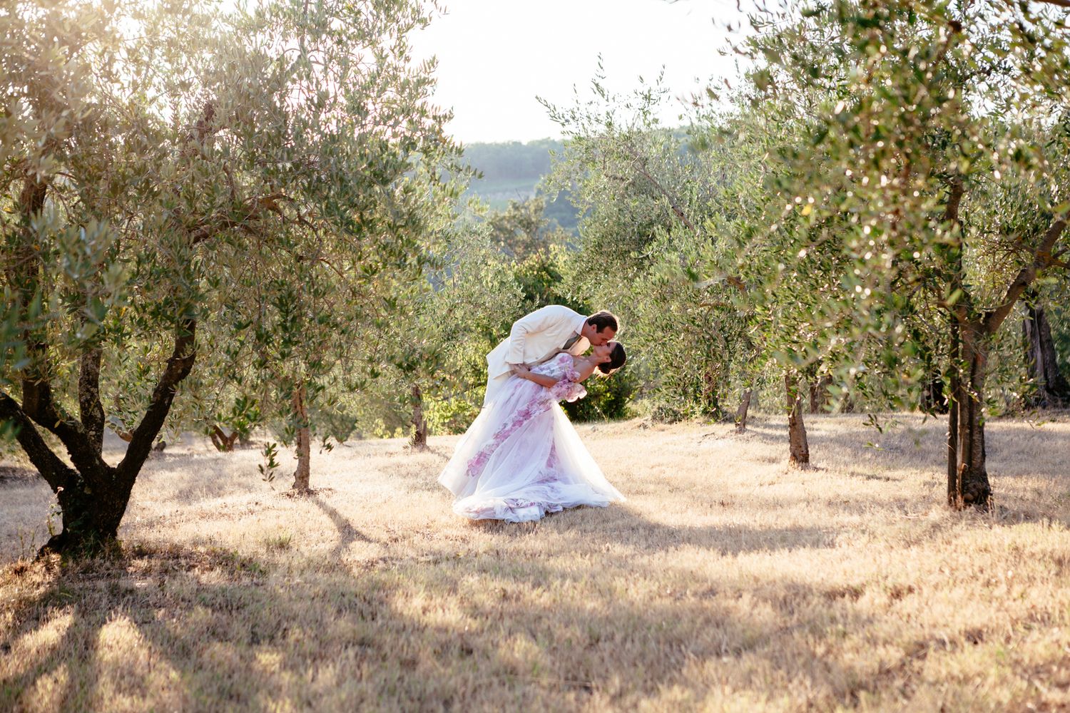 groom dips and kisses bride in an olive grove