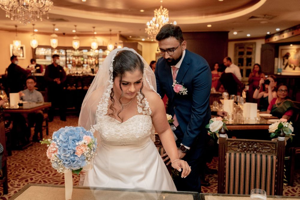 Wedding couple cuts their cake together during an elegant indoor reception with ornate decor and chandelier lighting.