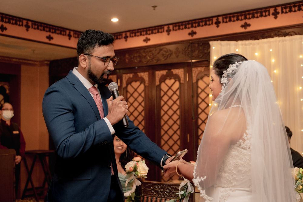 A couple participates in their wedding ceremony inside an elegantly decorated venue with string lights.