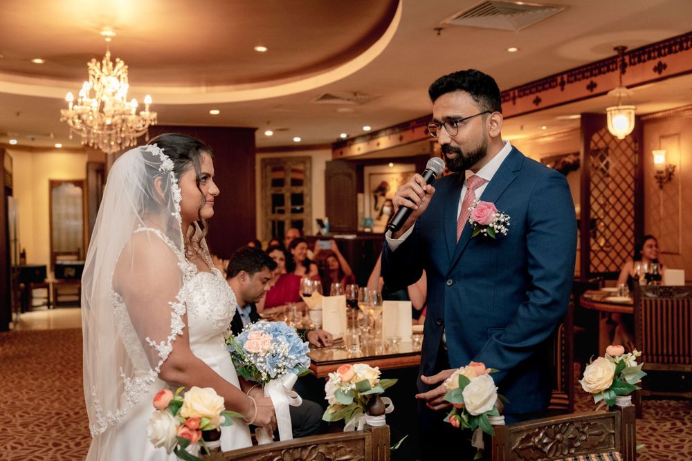 A couple exchanges vows during their wedding ceremony in an elegant ballroom with crystal chandeliers.