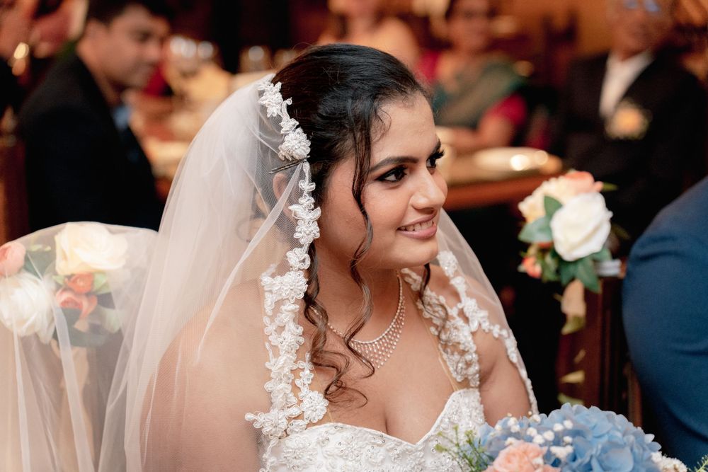 Bride in white lace dress and veil smiling during wedding reception.