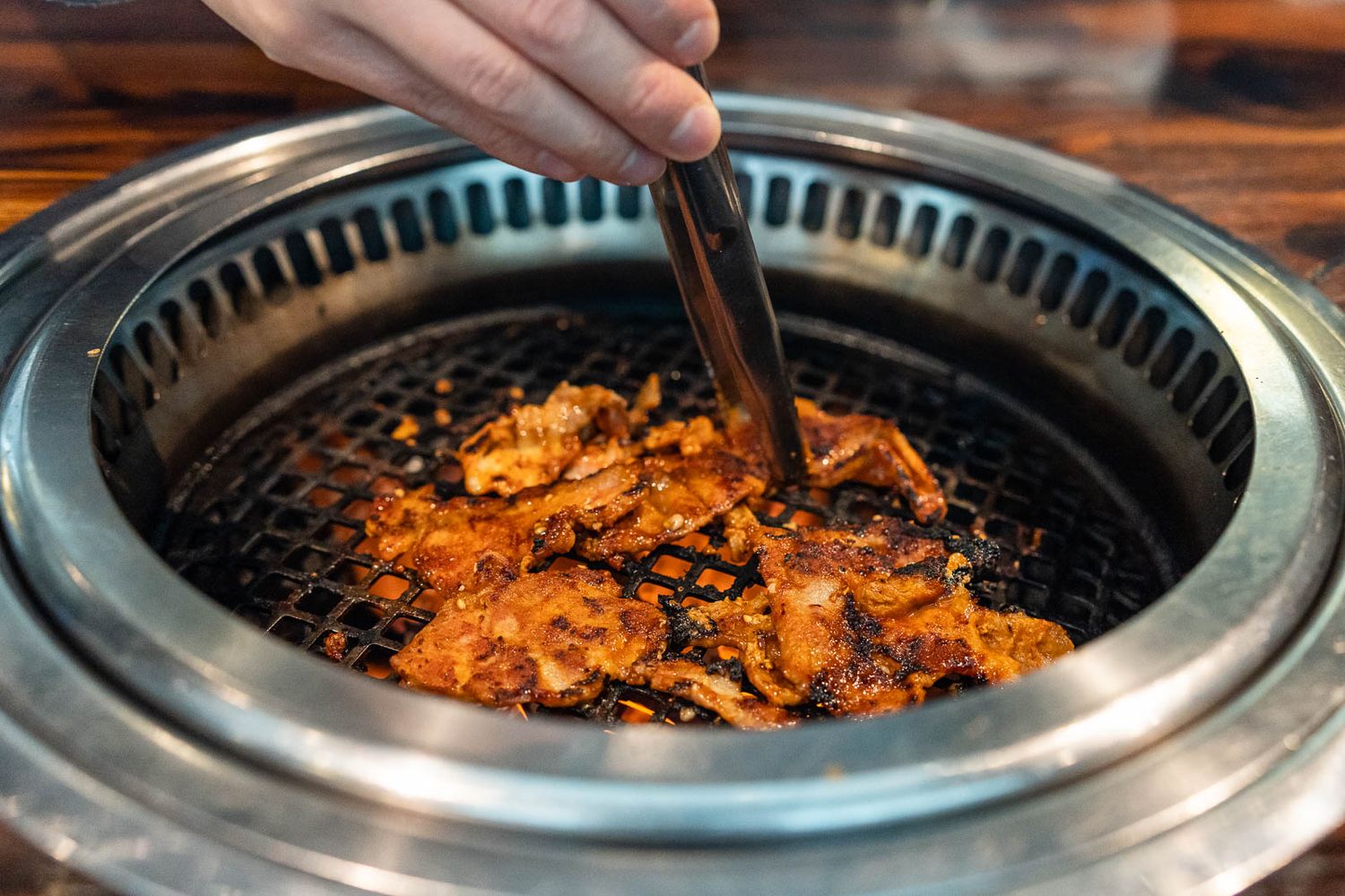 Photo of person using tongs to cook the meat at Gyu Kaku in Bellevue.