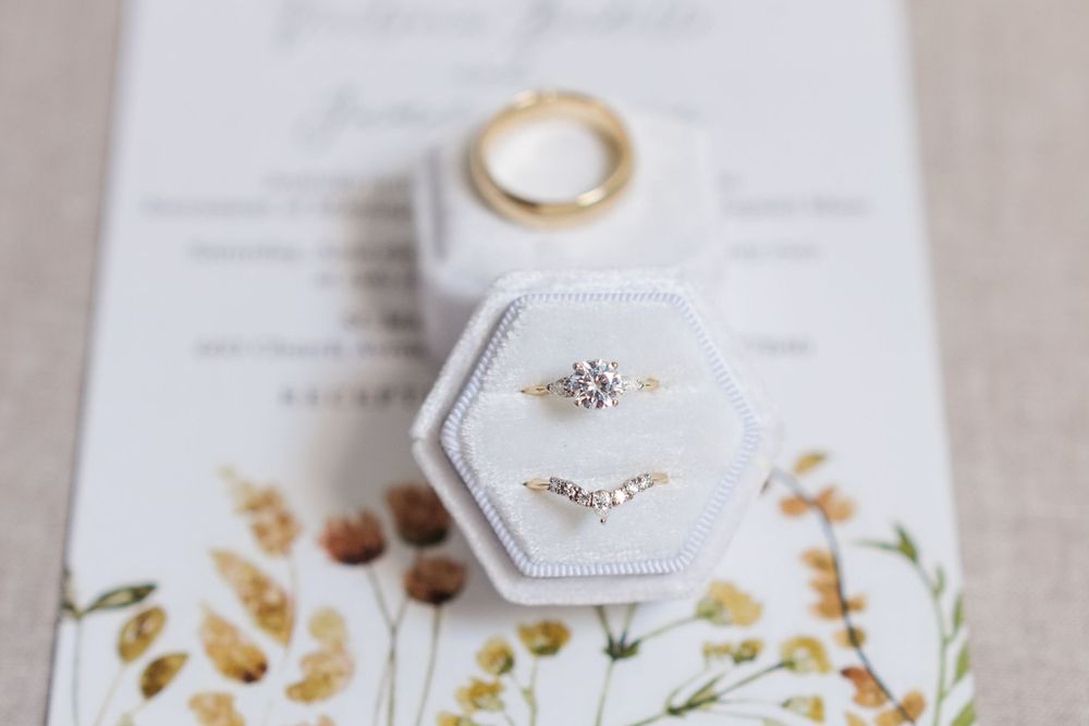 Wedding rings displayed in elegant hexagonal boxes with delicate floral decorations.