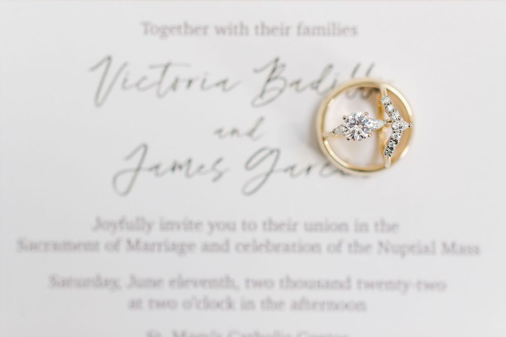 Wedding invitation with engagement ring casting shadow on elegant white paper.