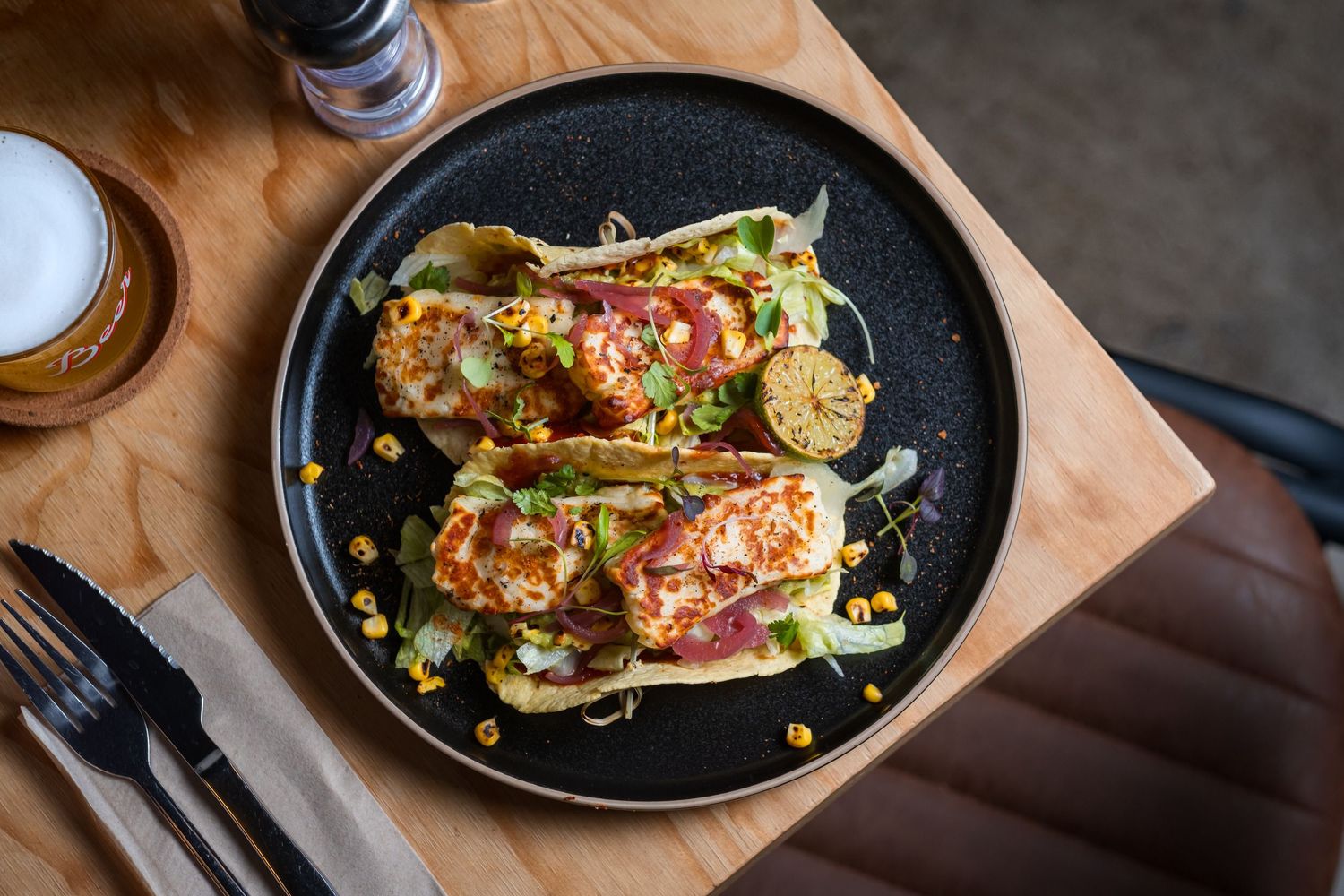 Close up of halloumi tacos on a plate with herbs sprinkled on top.
