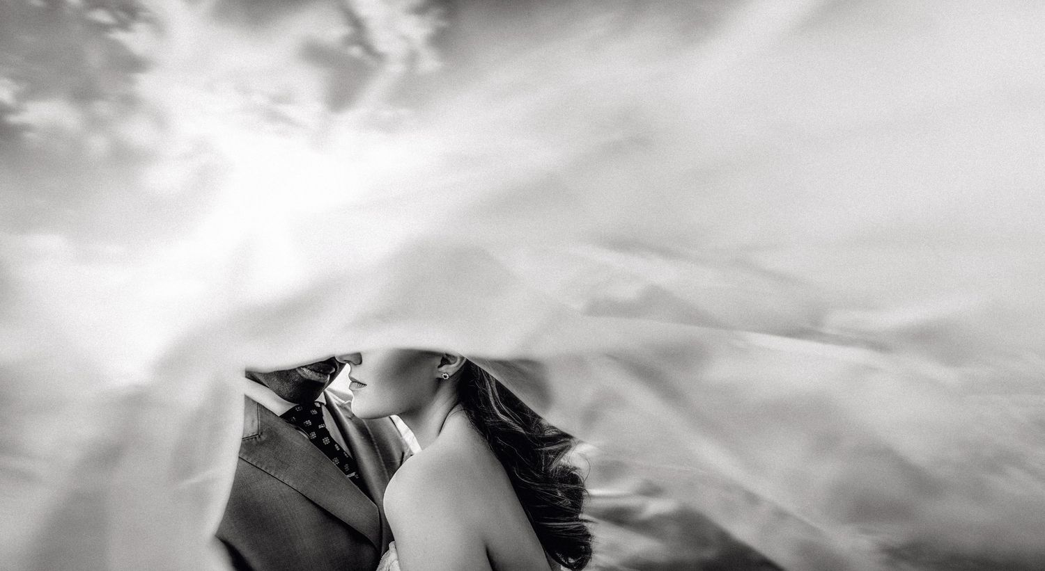 Dramatic black and white landscape panorama shot of mountains under cloudy skies.